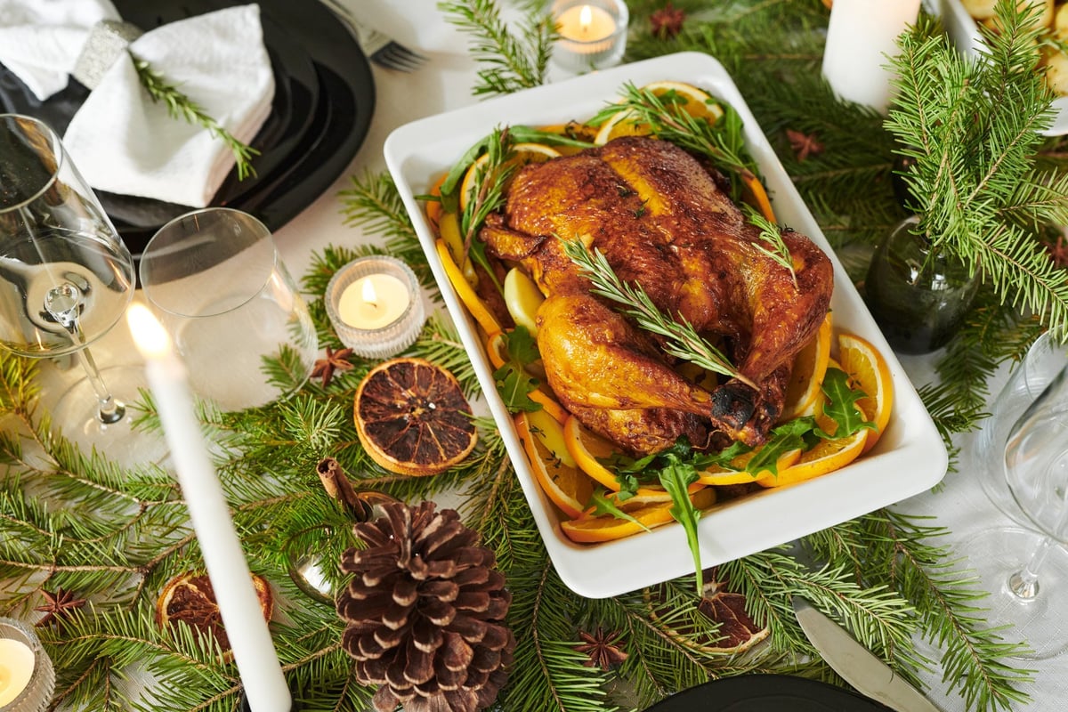 Whole roasted chicken garnished with rosemary and orange slices on a holiday table